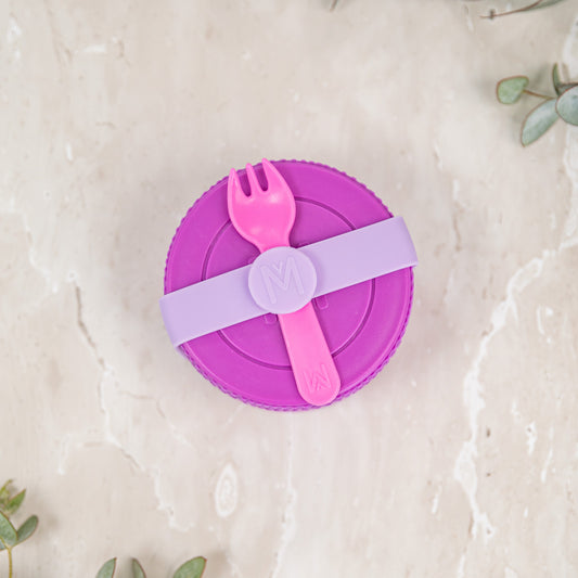 Purple lid with pink fork and spoon on a light beige background