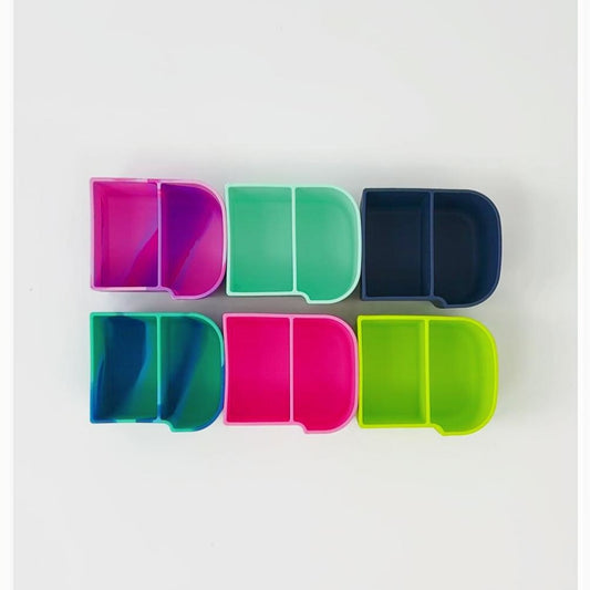 A set of colourful MontiiCo silicone snack trays arranged in a grid, with close‑up images showing the tray open to reveal compartments and an example of it being used to store small items like sticky notes and paper clips