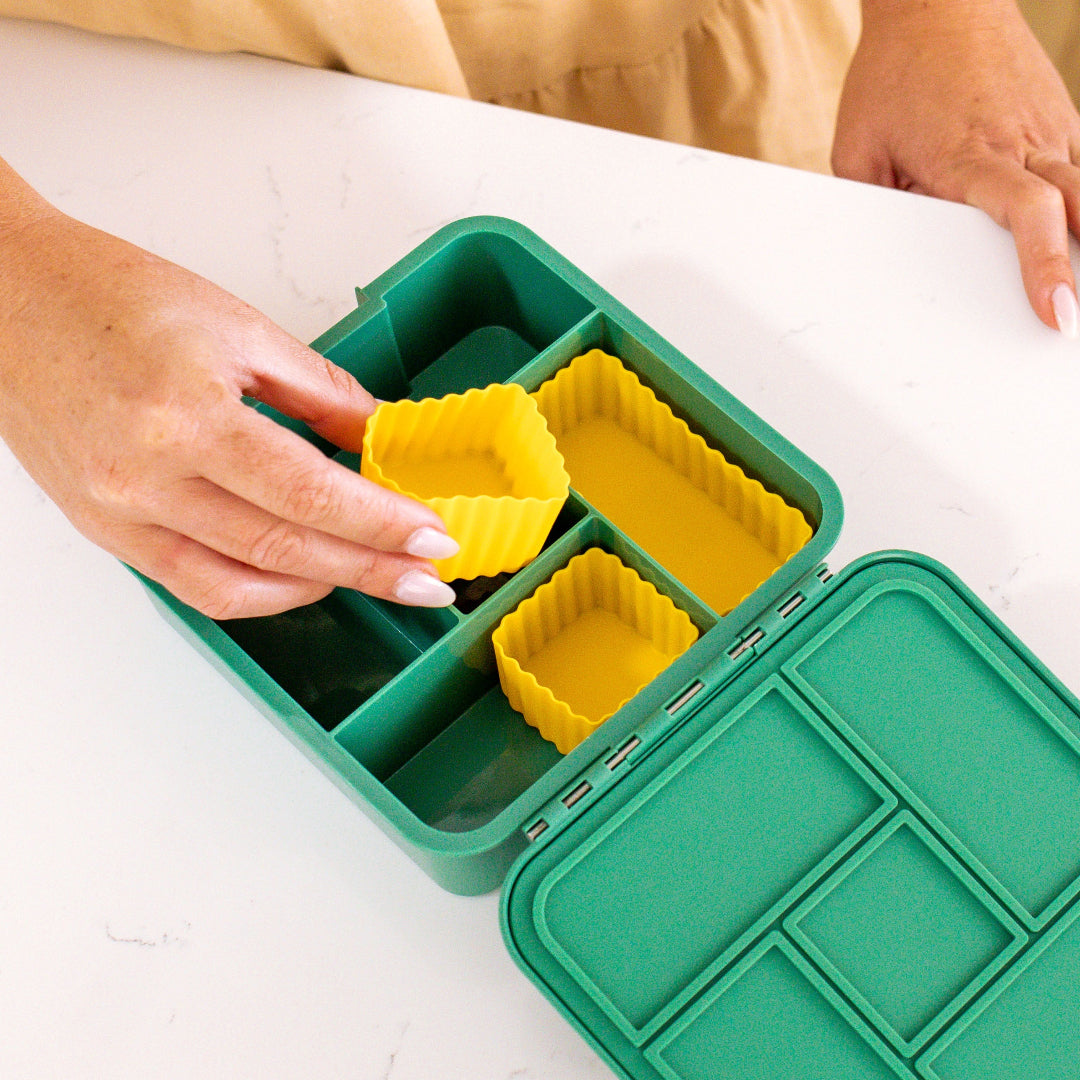 Set of mixed bento cups with fluted sides, shown in multiple sizes for organising snacks in green bento box.