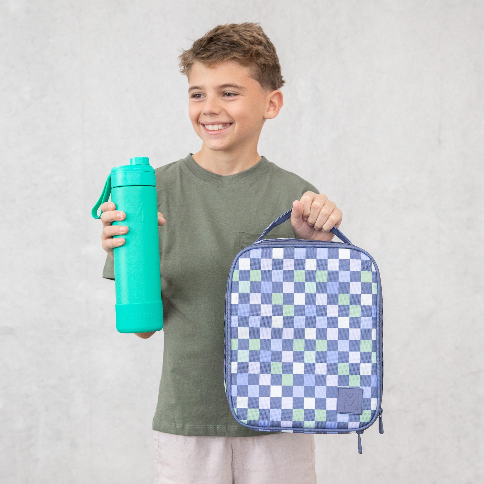 Child holding a teal water bottle and a blue checkered lunch bag against a light gray background