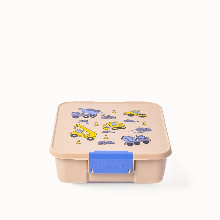 Front angle of closed beige MontiiCo Bento 5 lunch box showing blue latch and construction pattern lid.