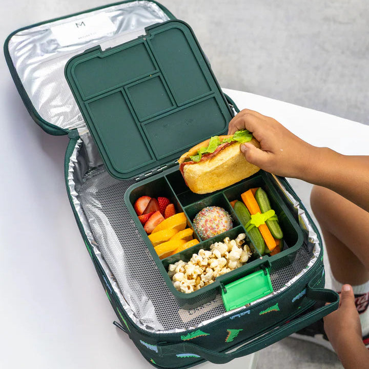 Overhead lifestyle shot of a child taking a burger out of an open packed MontiiCo Bento 5 Dinosaur lunch box inside an insulated bag.