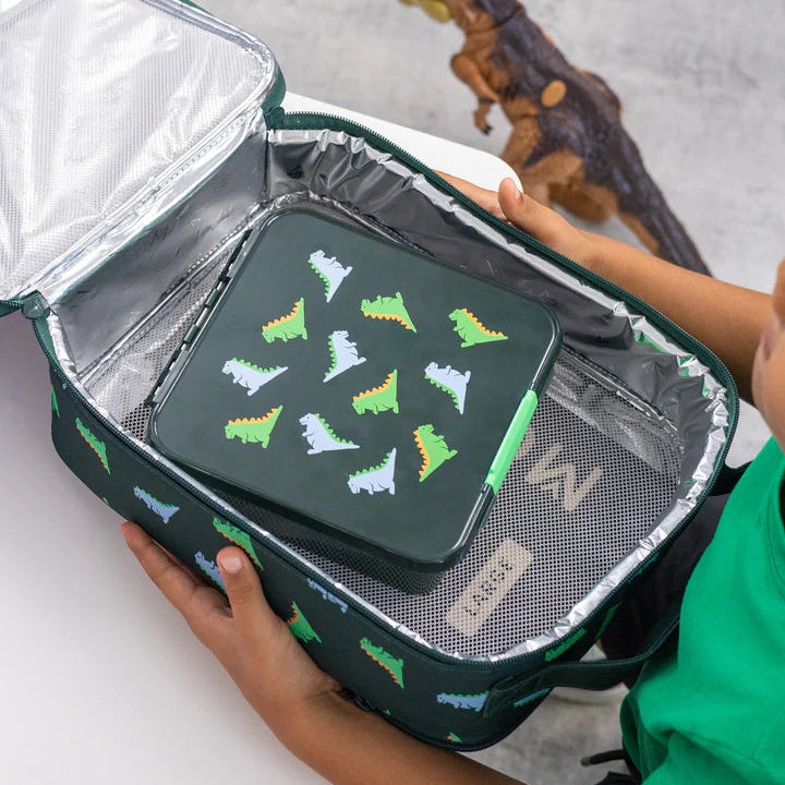 Closed MontiiCo Bento 5 Dinosaur lunch box resting inside an open matching insulated lunch bag held by a child