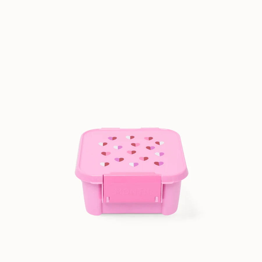 Front-facing view of the closed pink MontiiCo Bento 2 snack box showing the front latch and compact design.
