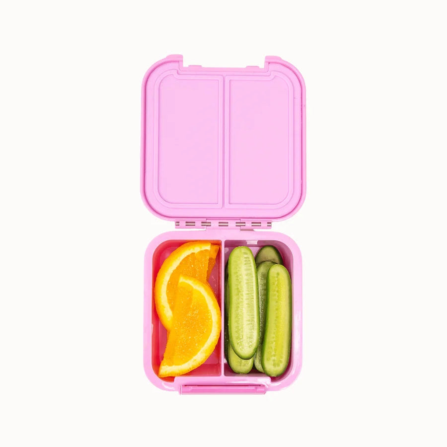 Top view of the open pink MontiiCo Bento 2 snack box packed with fresh orange slices and cucumber spears in its two compartments.