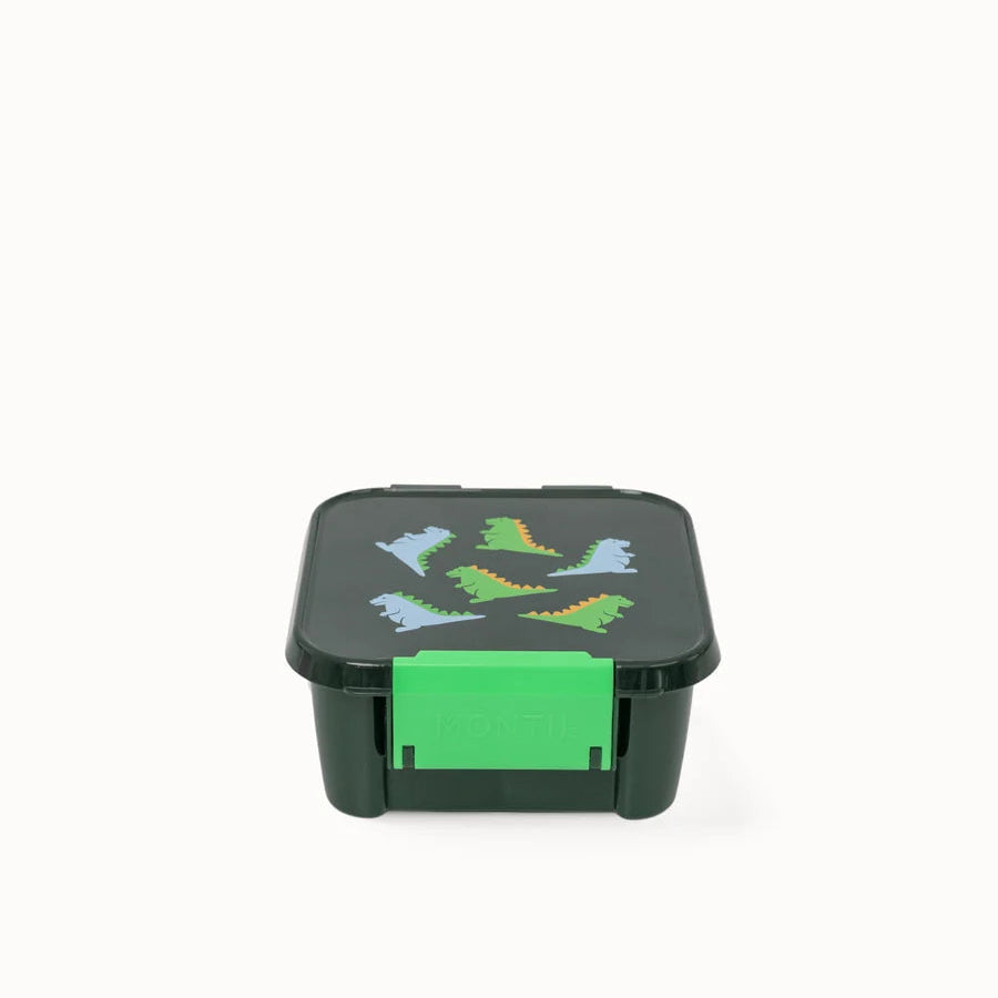 Angled front view of the closed MontiiCo Bento 2 Dinosaur snack box showing the bright green front latch.