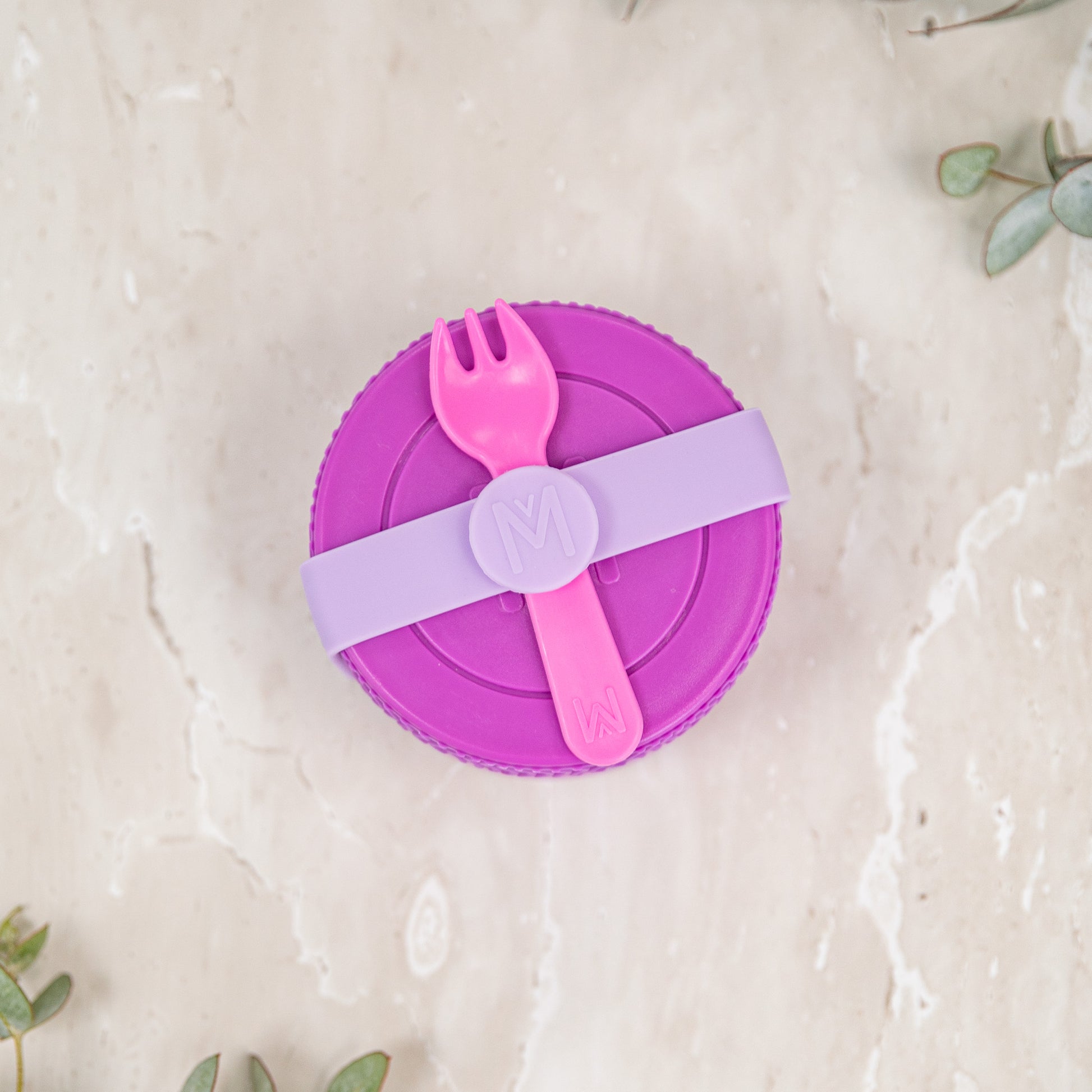 Purple lid with pink fork and spoon on a light beige background