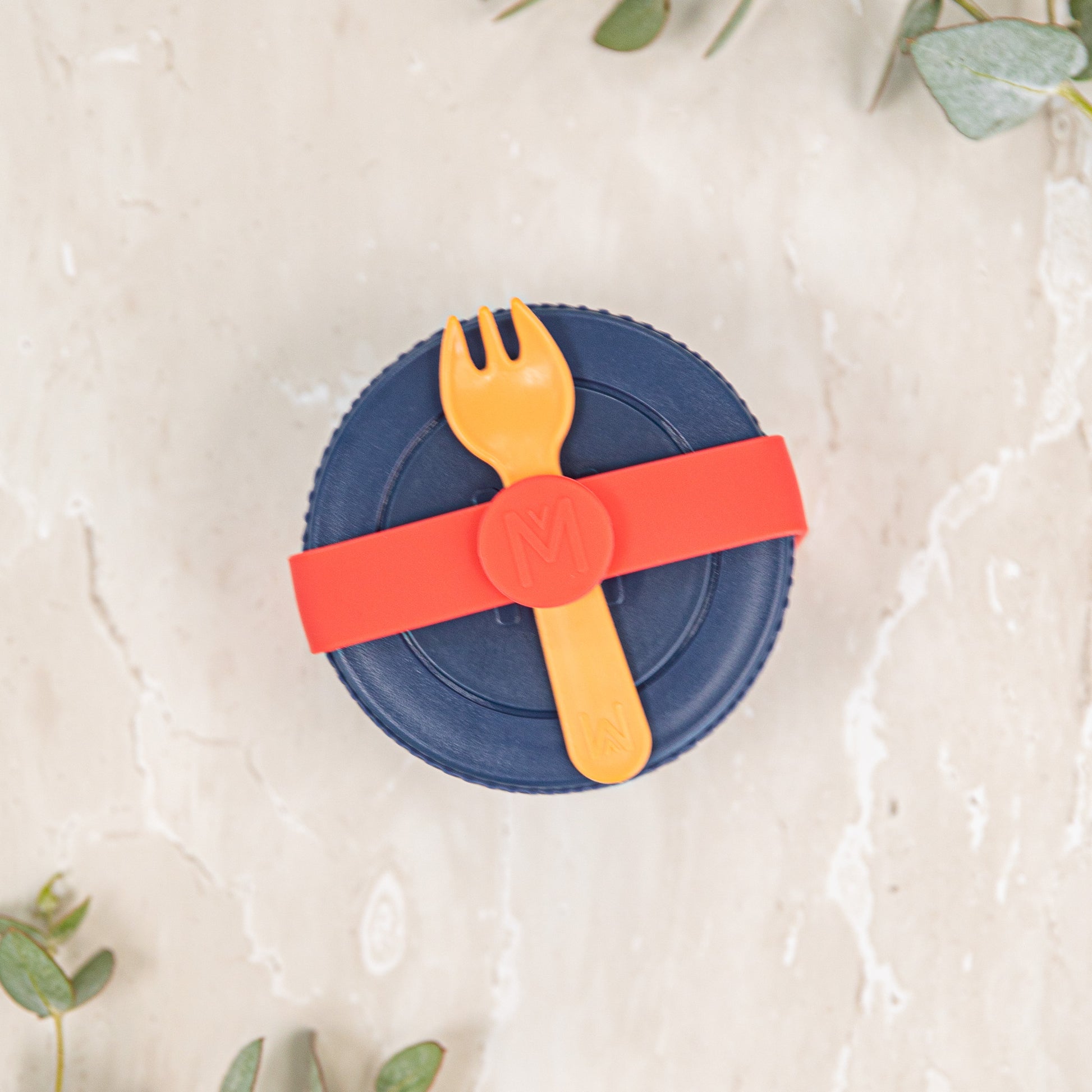 Blue lid with a red band and yellow fork on a light background