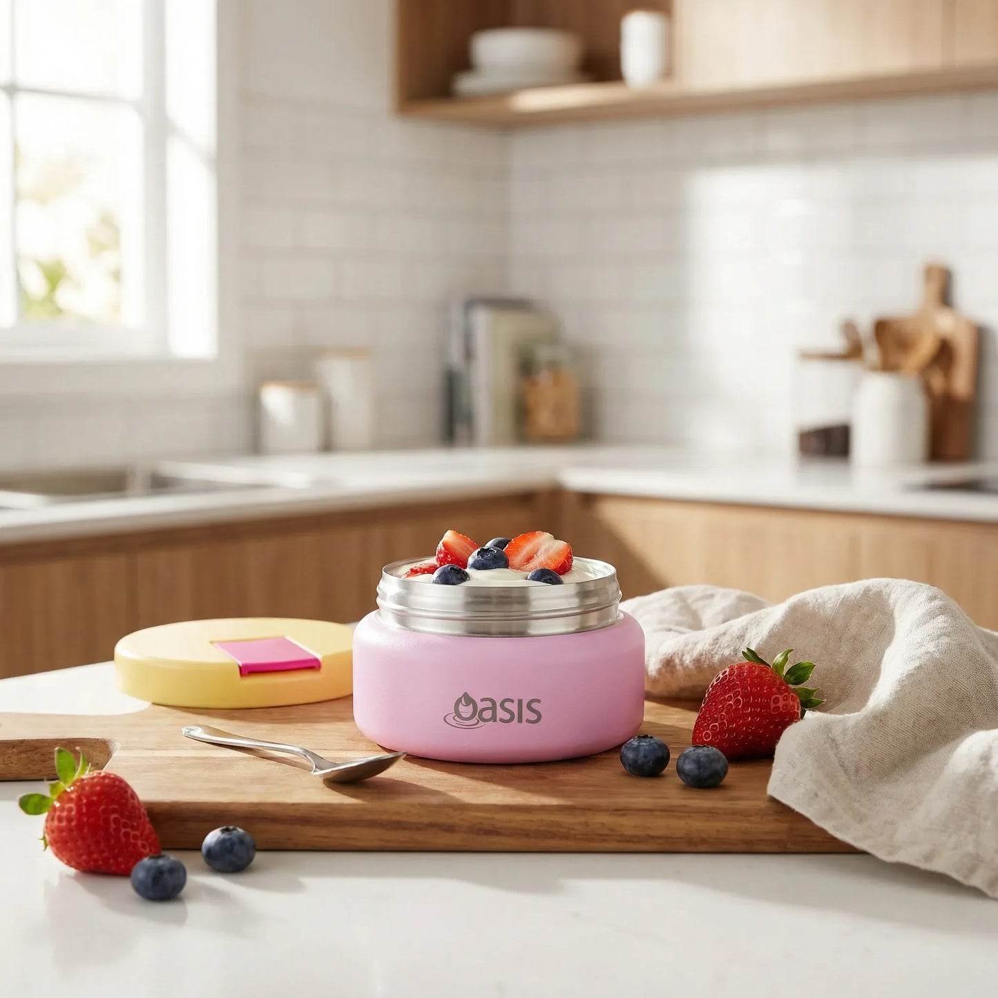 Pink insulated food container with strawberries and blueberries on a kitchen counter