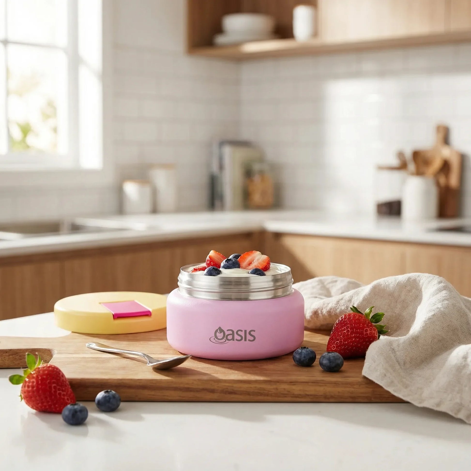 Pink insulated food container with strawberries and blueberries on a kitchen counter