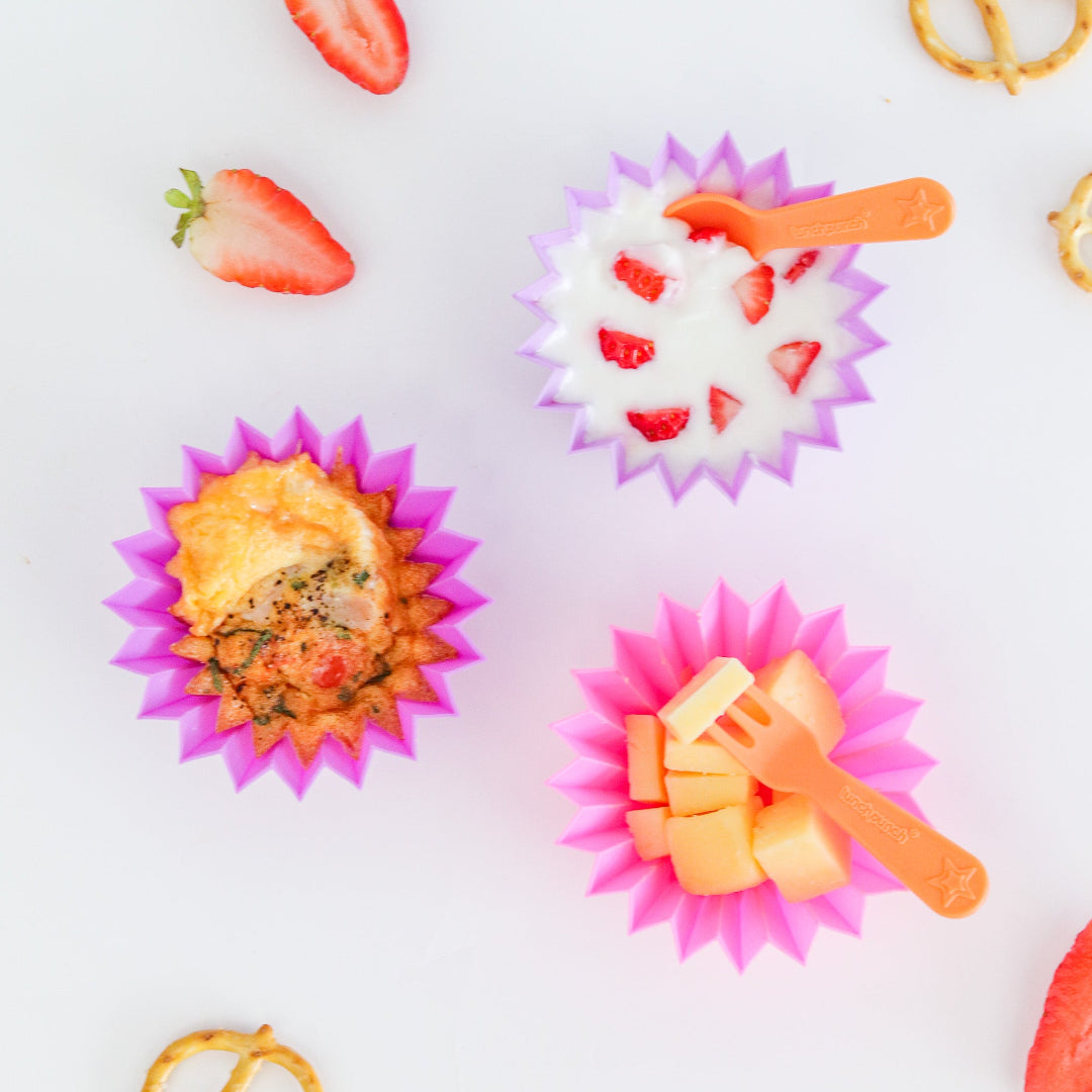 Colourful blush jumbo silicone snack cups used as bento cups to separate fruit and snacks in a lunchbox.