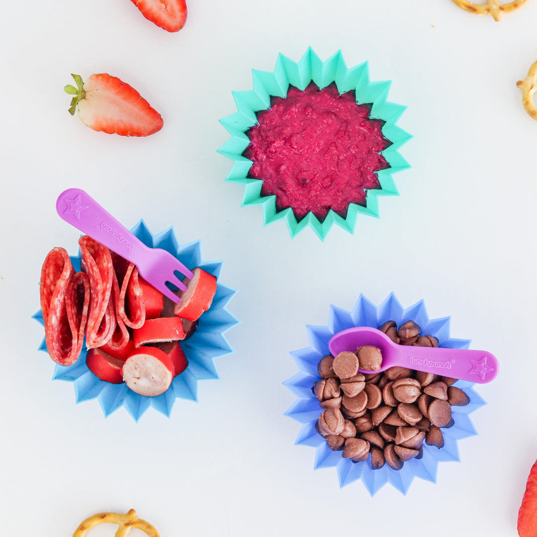 Colorful silicone food molds with food items on a white background