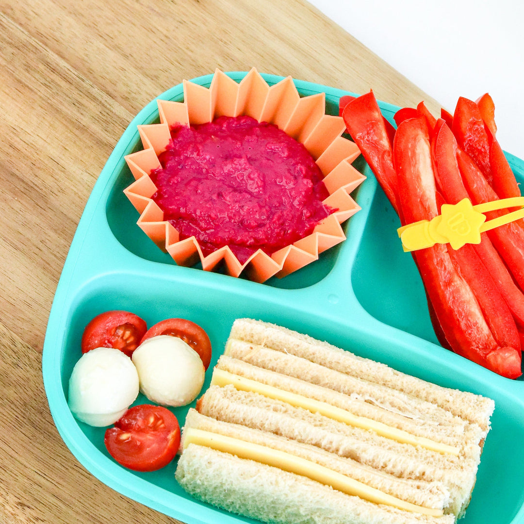 in a colourful kids’ lunchbox, perfect for bento accessories and lunch packing containing a sandwich, fruit, and other snacks on a wooden surface.