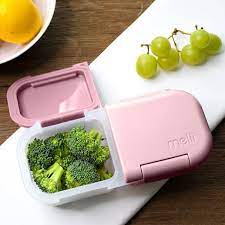 Pink bento box with broccoli and grapes on a wooden table