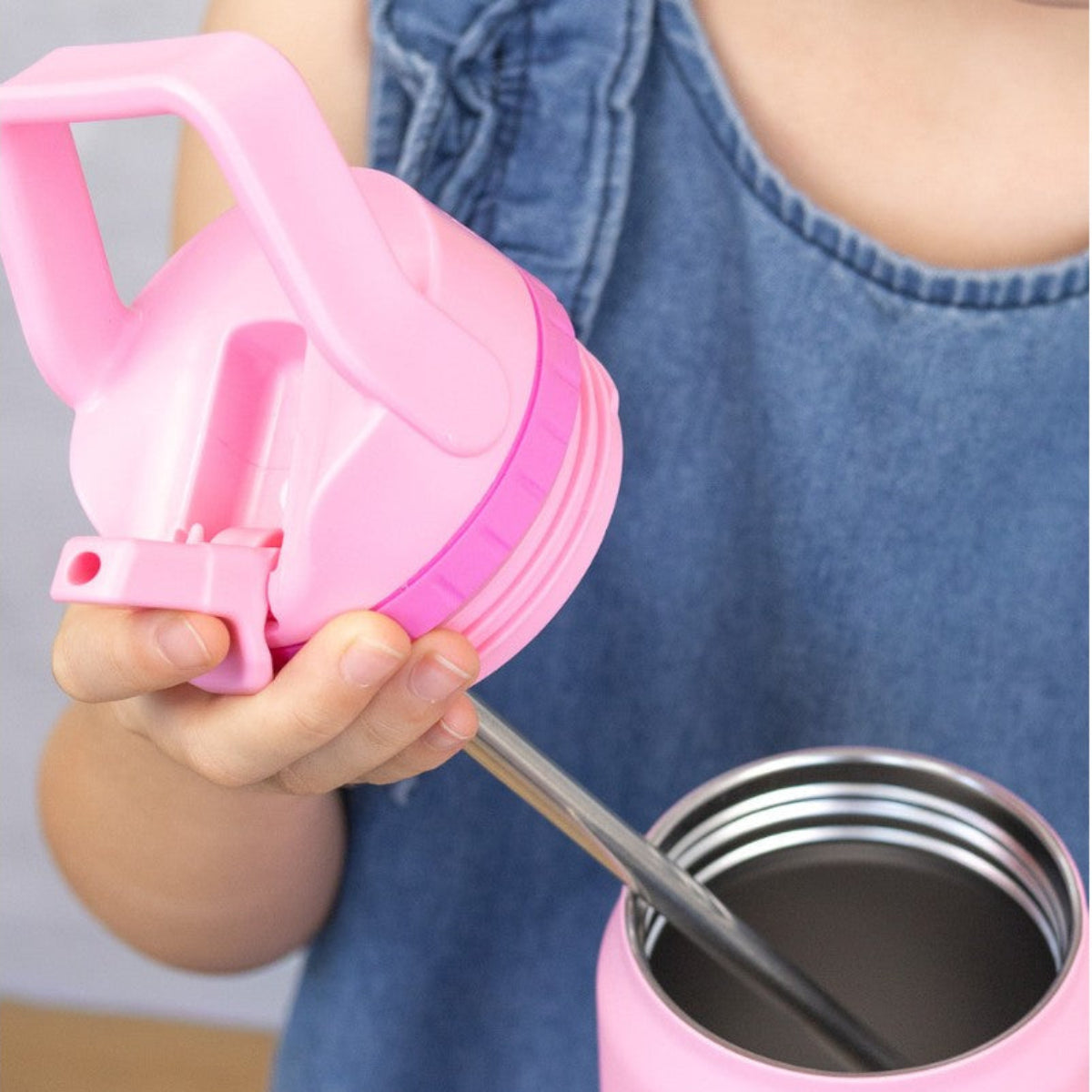 Person holding a pink 750ml MontiiCo Sport Drink Bottle with a straw lid