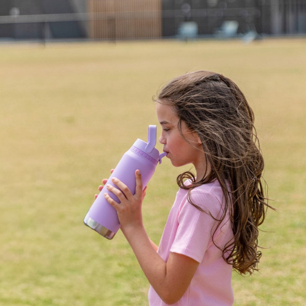 Girl drinking from a MontiiCo 750ml Sport Drink Bottle - Lilac outdoors on grass