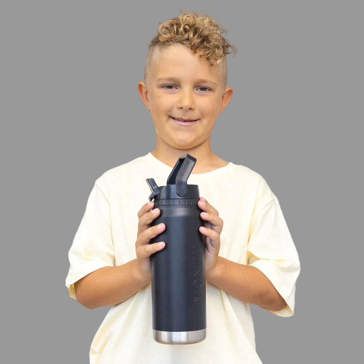 Child holding a MontiiCo Midnight 750ml Sport Drink Bottlee against a plain background