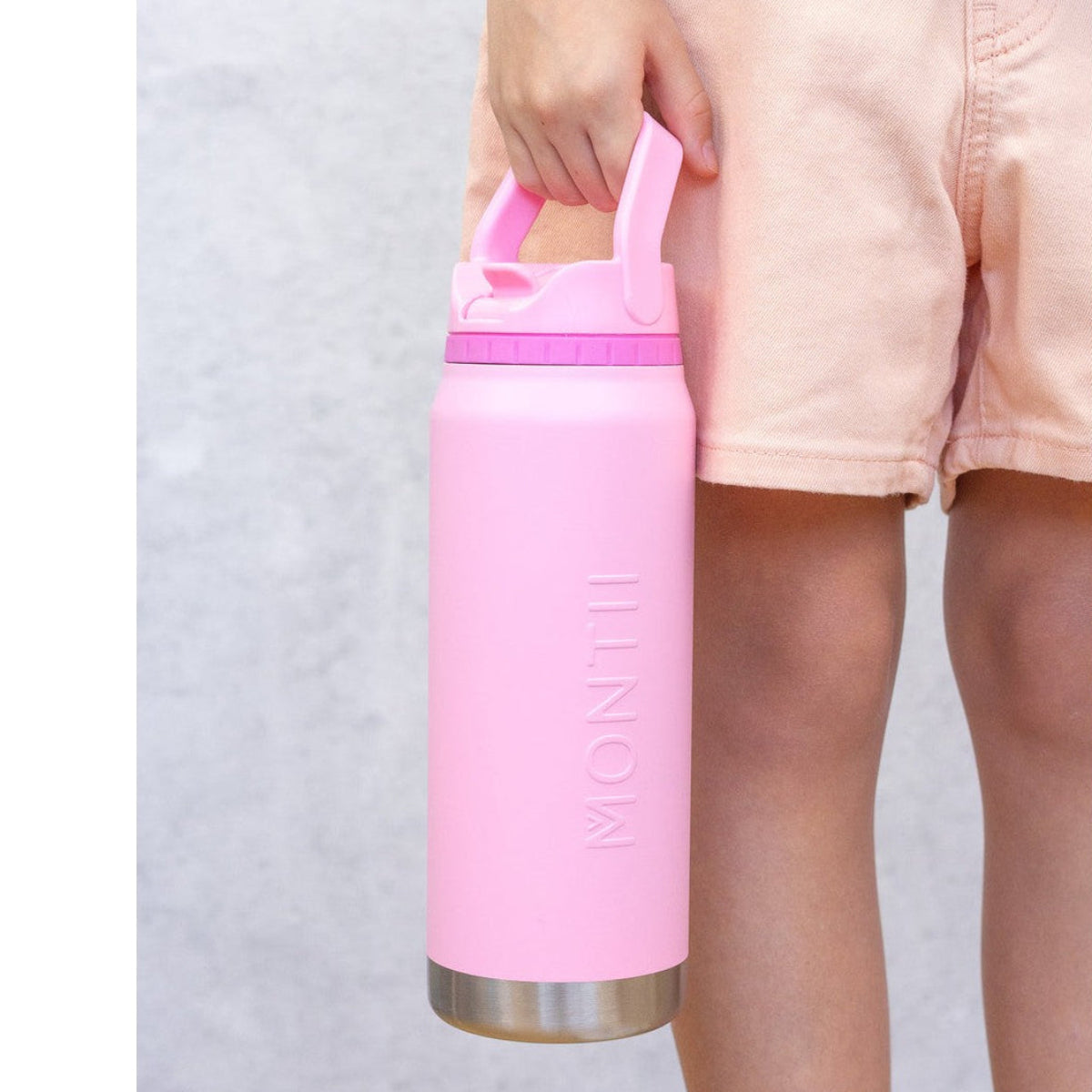 Person holding a pink water bottle with a silver base against a light gray background