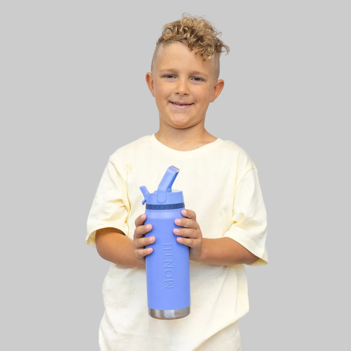 Child holding a blue water bottle with a straw lid against a plain background