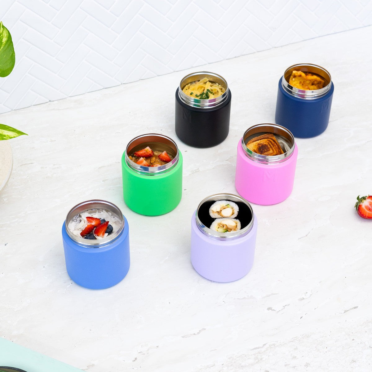 Set of colorful insulated food containers from Montiico with food inside on a white surface.