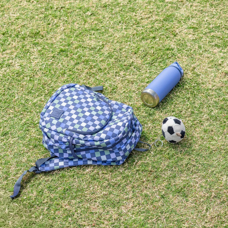 Blue checkered MontiiCo Mini Backpack - Checkmate, blue water bottle, and soccer ball on grass