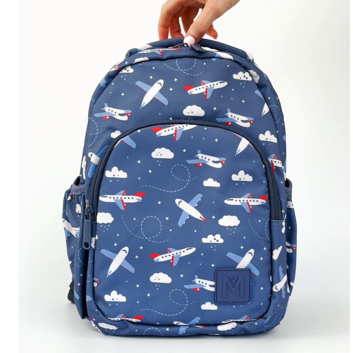 MontiiCo Mini Backpack - Jetset  with airplane pattern held by a hand on a white background
