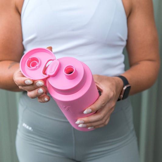 Person holding a bright pink MontiiCo Fusion bottle with an open flip-top lid during a workout.
