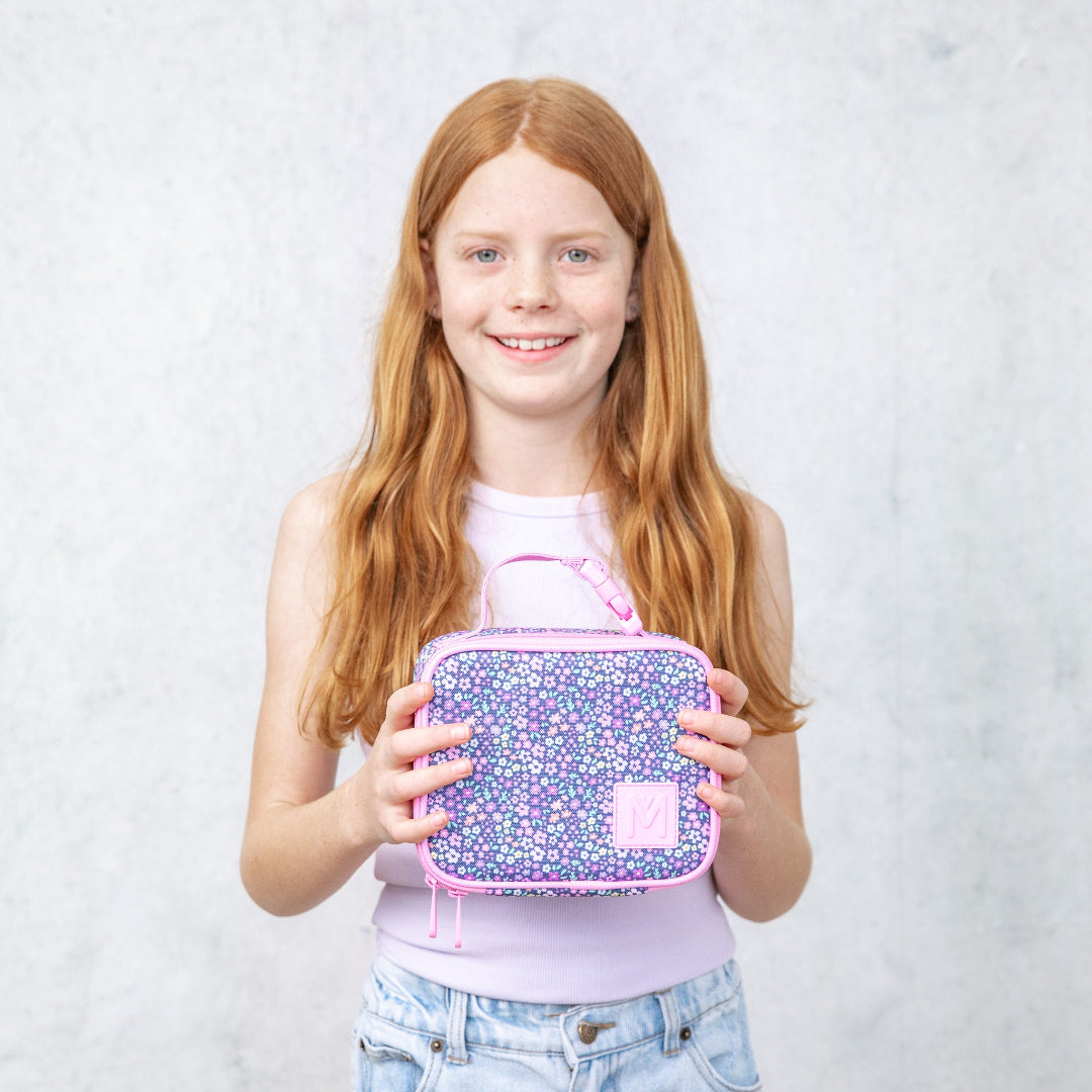 montiico mini meadow lunch bag shown being held to demonstrate compact size and portability