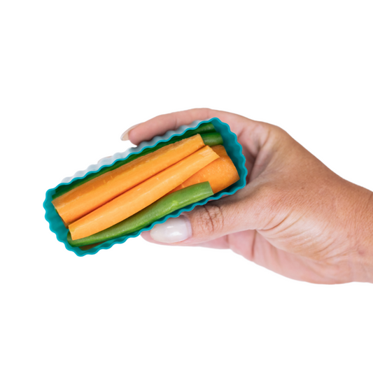 Hand holding MontiiCo mixed bento cups with fluted sides, shown in pine green for organising snacks in lunch boxes