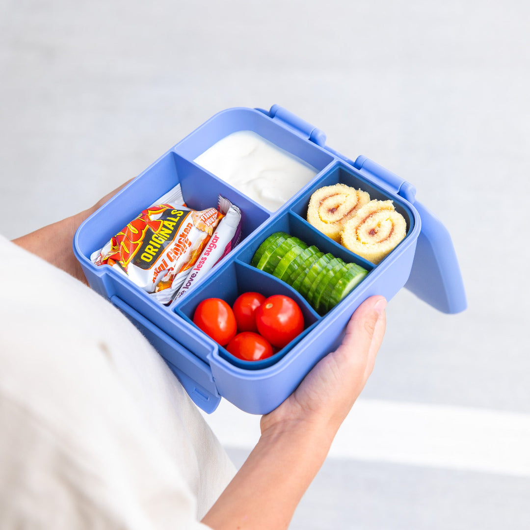 Silicone bite tray by MontiiCo in Navy with compartments containing snacks and vegetables on a light gray background