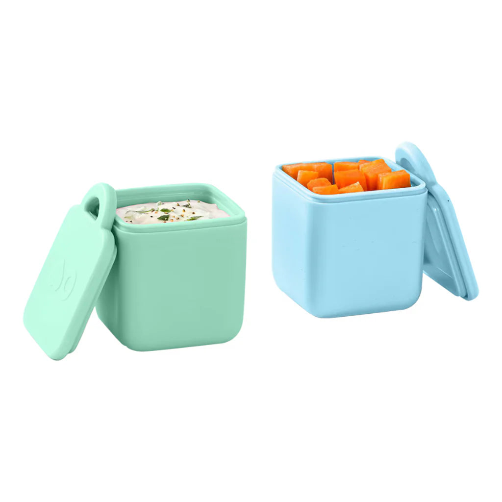 omie dip pack of 2 in blue and mint with lids on, baby bento. Two silicone snack containers, one green and one blue, on a white background.