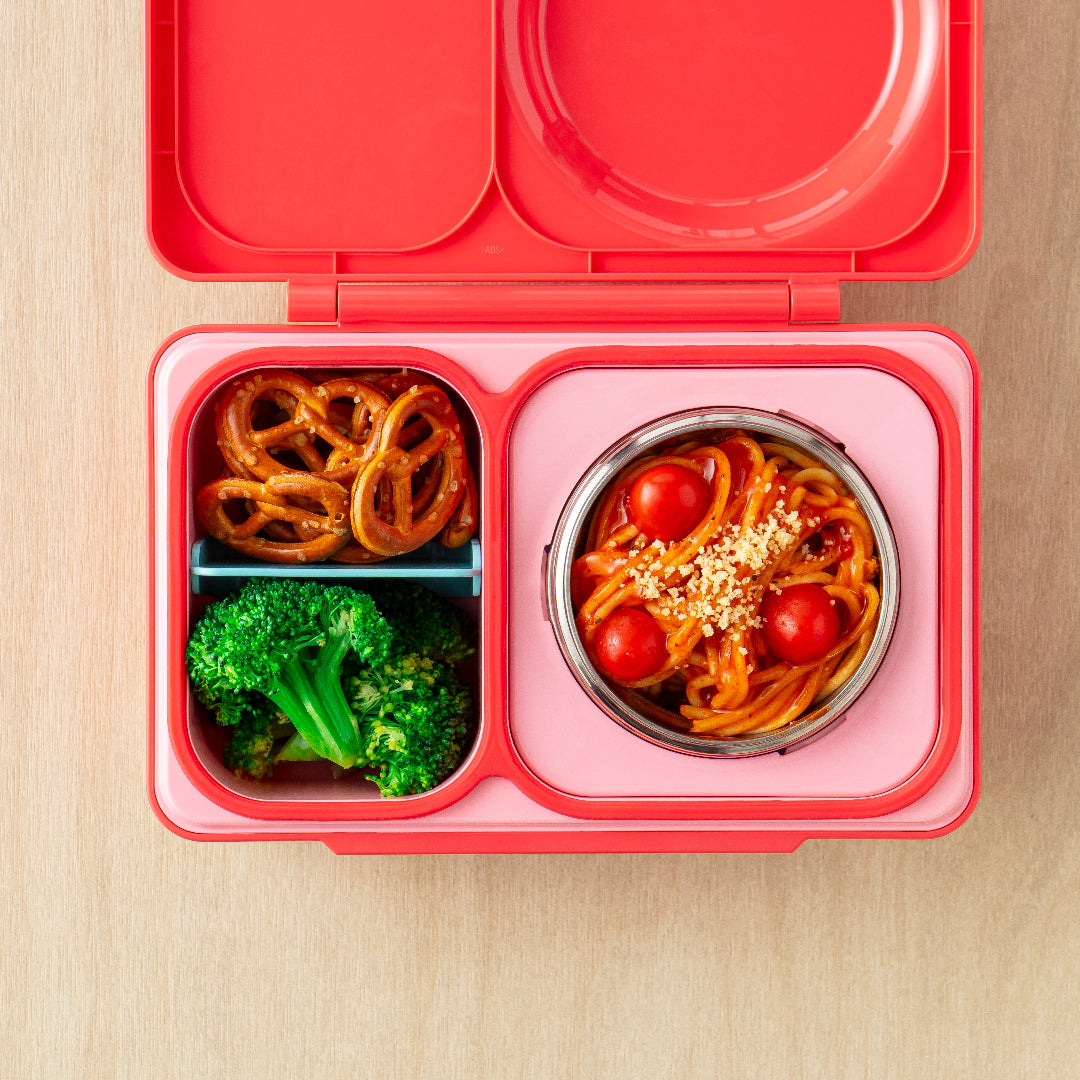 Cherry Pink OmieBox Up hot and cold bento box filled with wraps, vegetables and fruit in deep compartments.