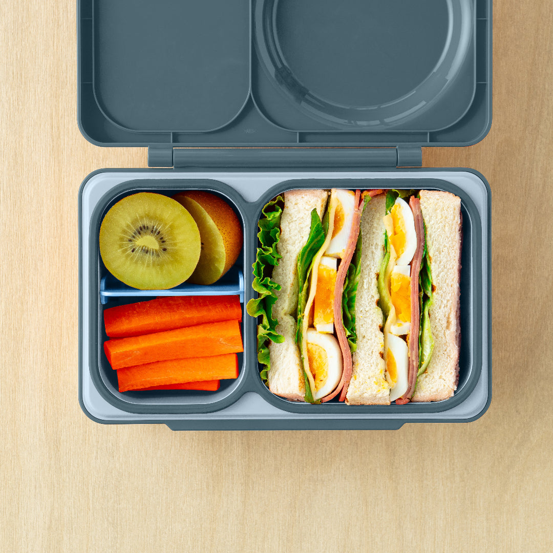 Top view of Graphite OmieBox Up hot and cold bento box as a practical grown up lunch container filled with assorted foods.