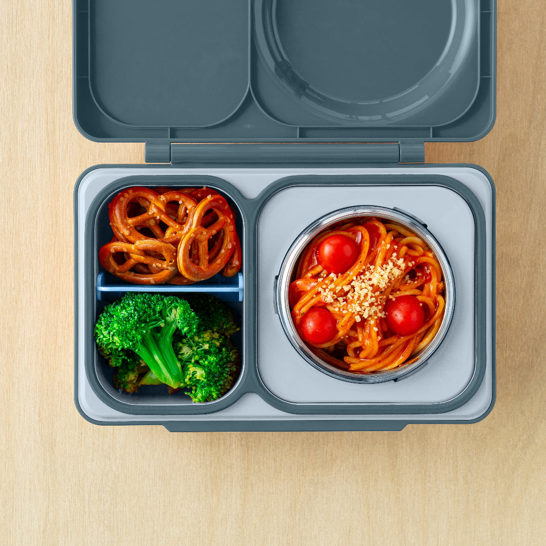 Top view of the Graphite OmieBox Up hot and cold bento box showing deep compartments filled with pasta, pretzels and broccoli as a grown up lunch container.