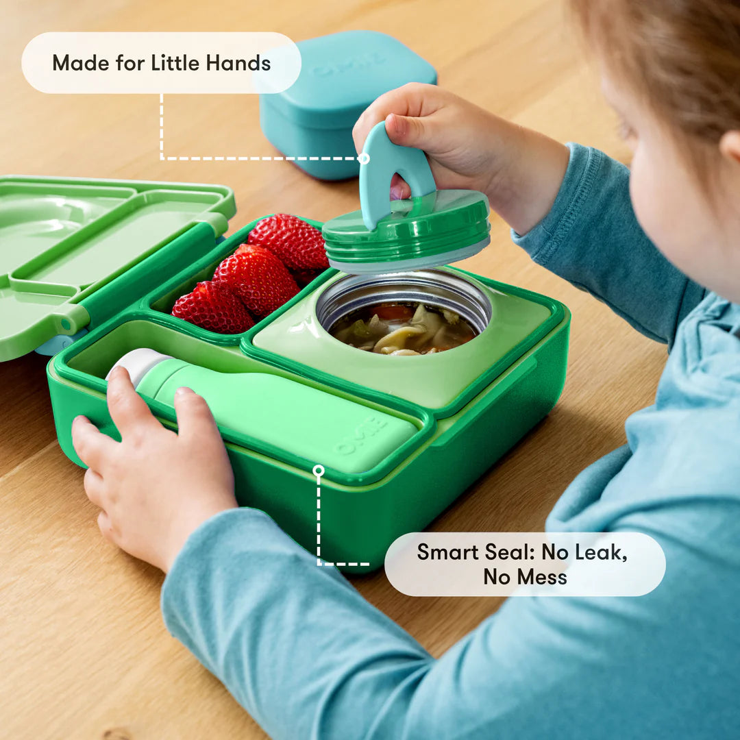 Preparing food in the Apple Green OmieBox V2 leakproof bento lunch box with divided compartments.