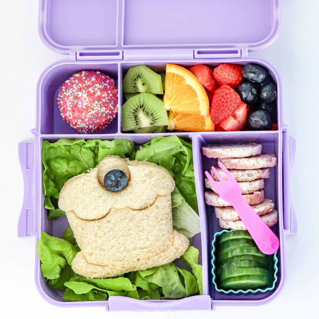 Purple bento box with a variety of food including a sandwich shaped like a frog, fruits, and vegetables.