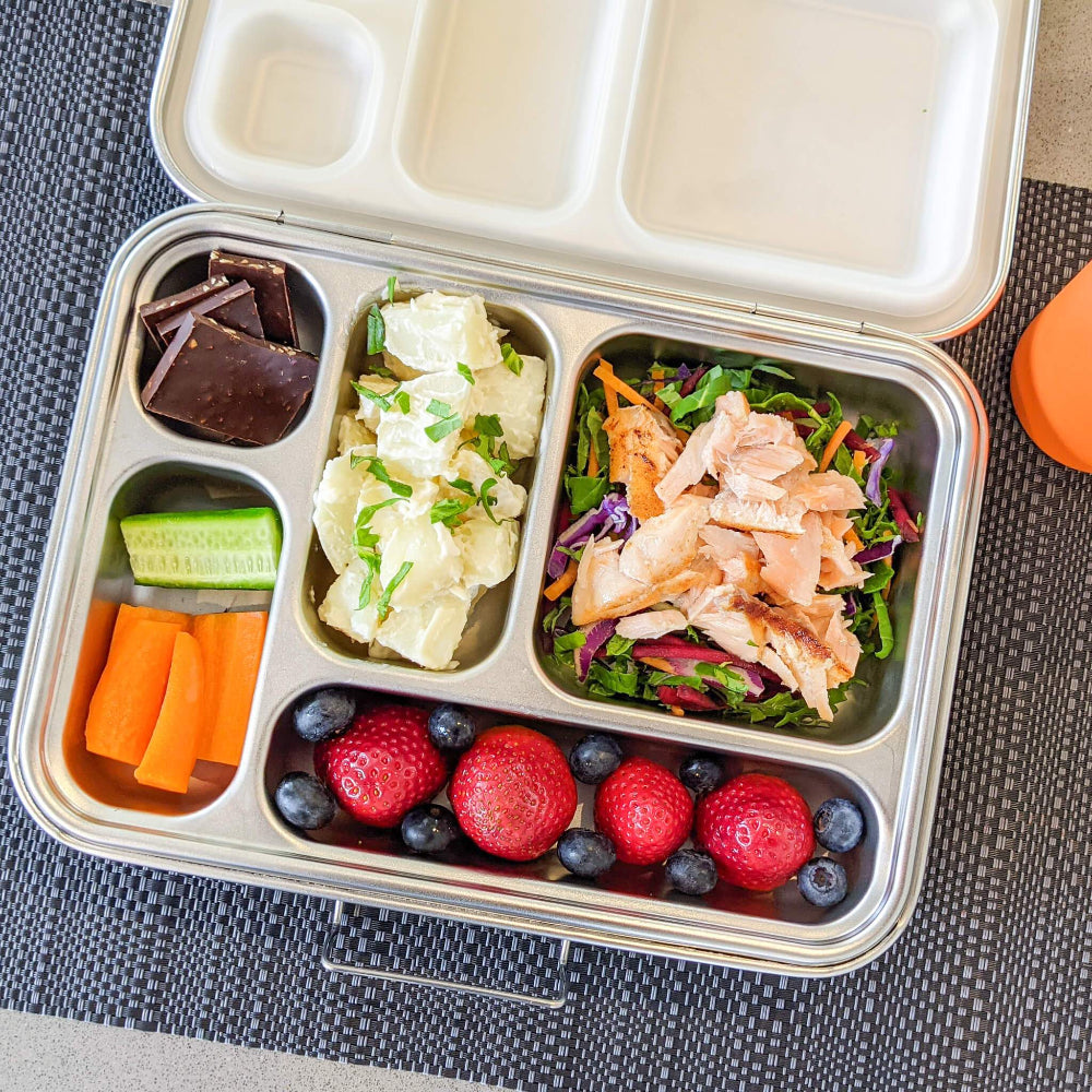 Ecococoon stainless steel leakproof lunch box with five compartments shown on table placemat filled with food to highlight its durable reusable lunch box design