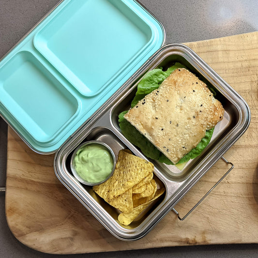 Ecococoon stainless steel leakproof bento box with two compartments and mint‑green lid, shown filled with food to highlight its durable metal lunch box design.