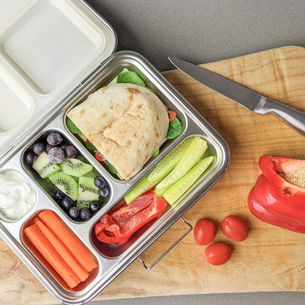 Ecococoon stainless steel leakproof bento box with five compartments and polished metal finish, shown on wooden chopping board filled with food to highlight its durable reusable lunch box design.