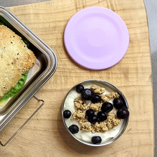 Ecococoon stainless steel snack pot with emerald purple lid shown beside fresh snacks, highlighting its durable metal bento‑style container design.