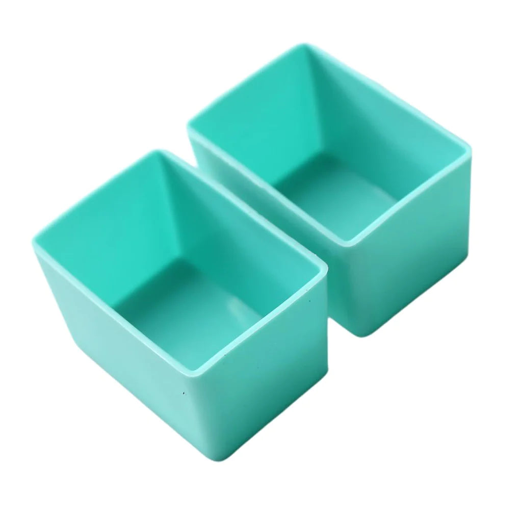 Two mint green rectangular silicone cups designed for holding food items, suitable for use in a dishwasher, oven, microwave, and freezer.